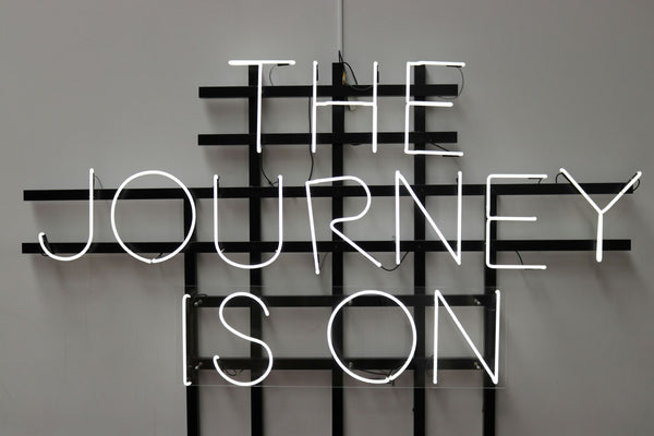 Neon sign saying "The Journey Is On"