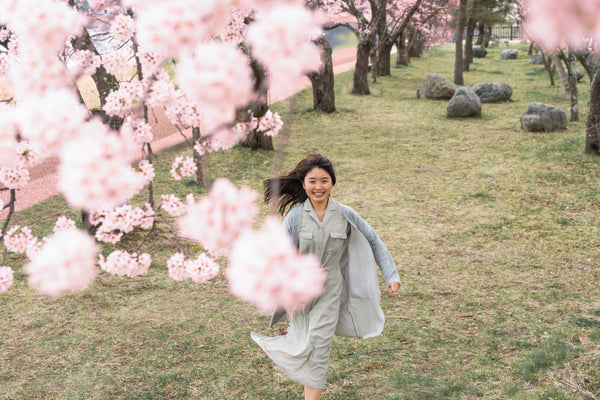 Young woman running towards the cherry blossoms
