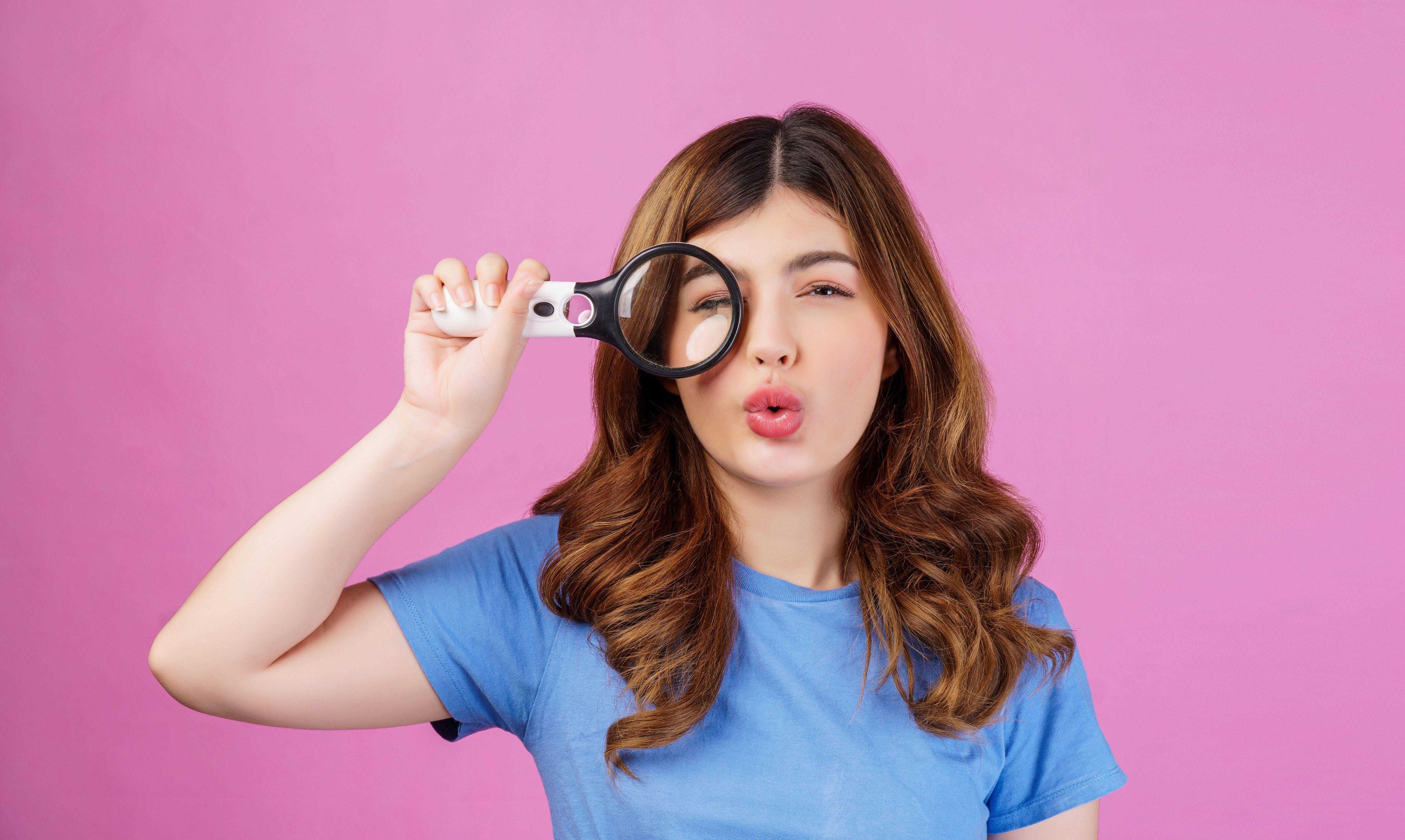 Woman looking through a magnifying glass